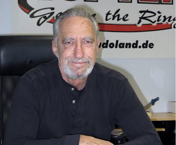 Mike Anderson on his 83rd birthday, seated in front of a Top Ten banner