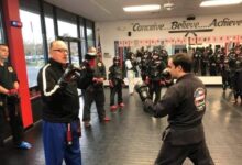 Grand Master Jeff Smith holding focus mitts for a student while the class waits behind him