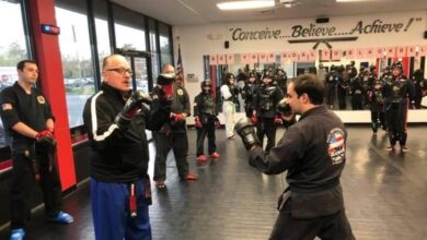 Grand Master Jeff Smith holding focus mitts for a student while the class waits behind him