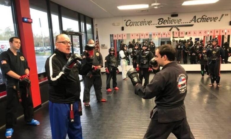 Grand Master Jeff Smith holding focus mitts for a student while the class waits behind him