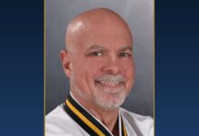 Chief Master Greg Moody, Ph.D., smiling, in his Black Belt uniform