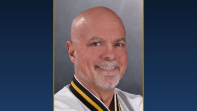 Chief Master Greg Moody, Ph.D., smiling, in his Black Belt uniform