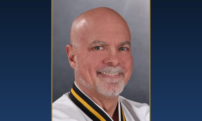 Chief Master Greg Moody, Ph.D., smiling, in his Black Belt uniform